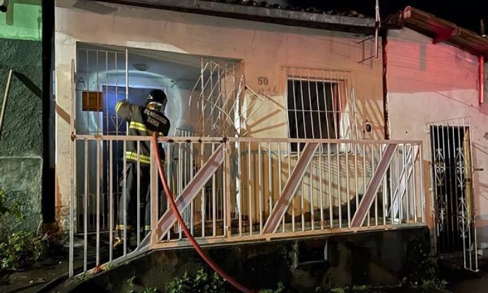 imagem da casa e bombeiros tentando apagar o incêndio